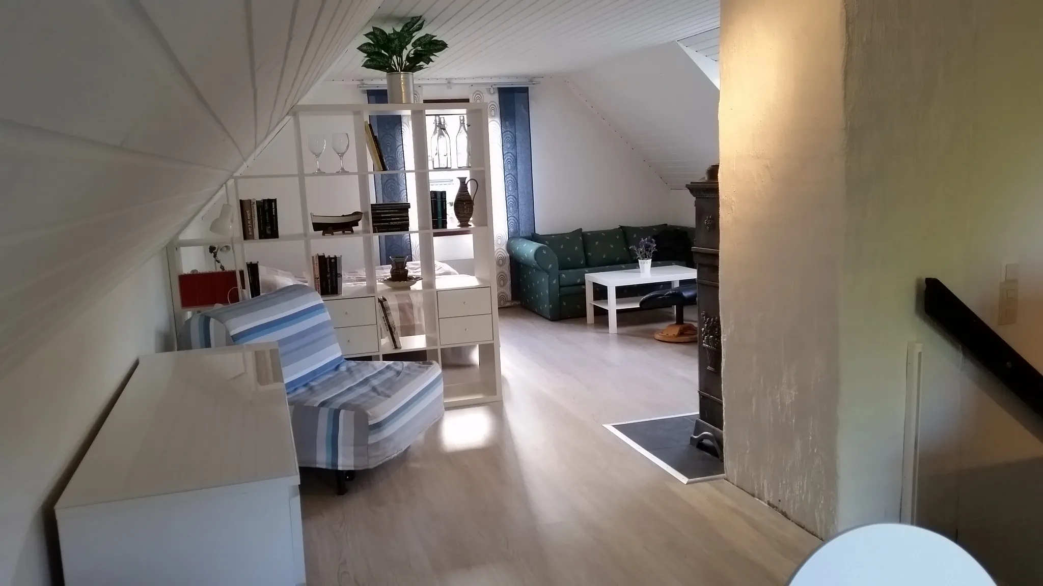 Living area with a sofa, low table and a tall antique cast-iron stove