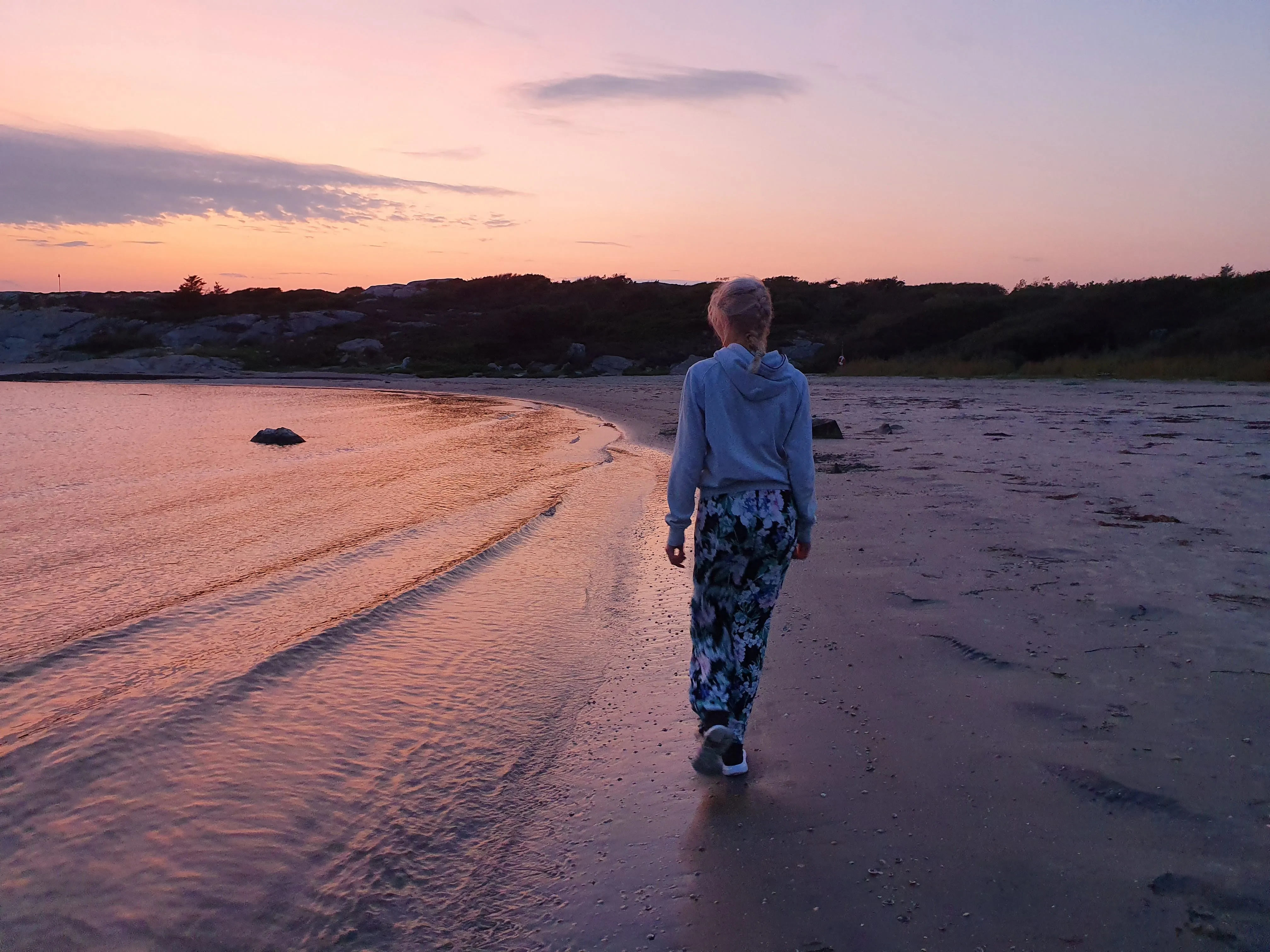 Sunset walk along the water’s edge, the pink sky reflected in the wet sand